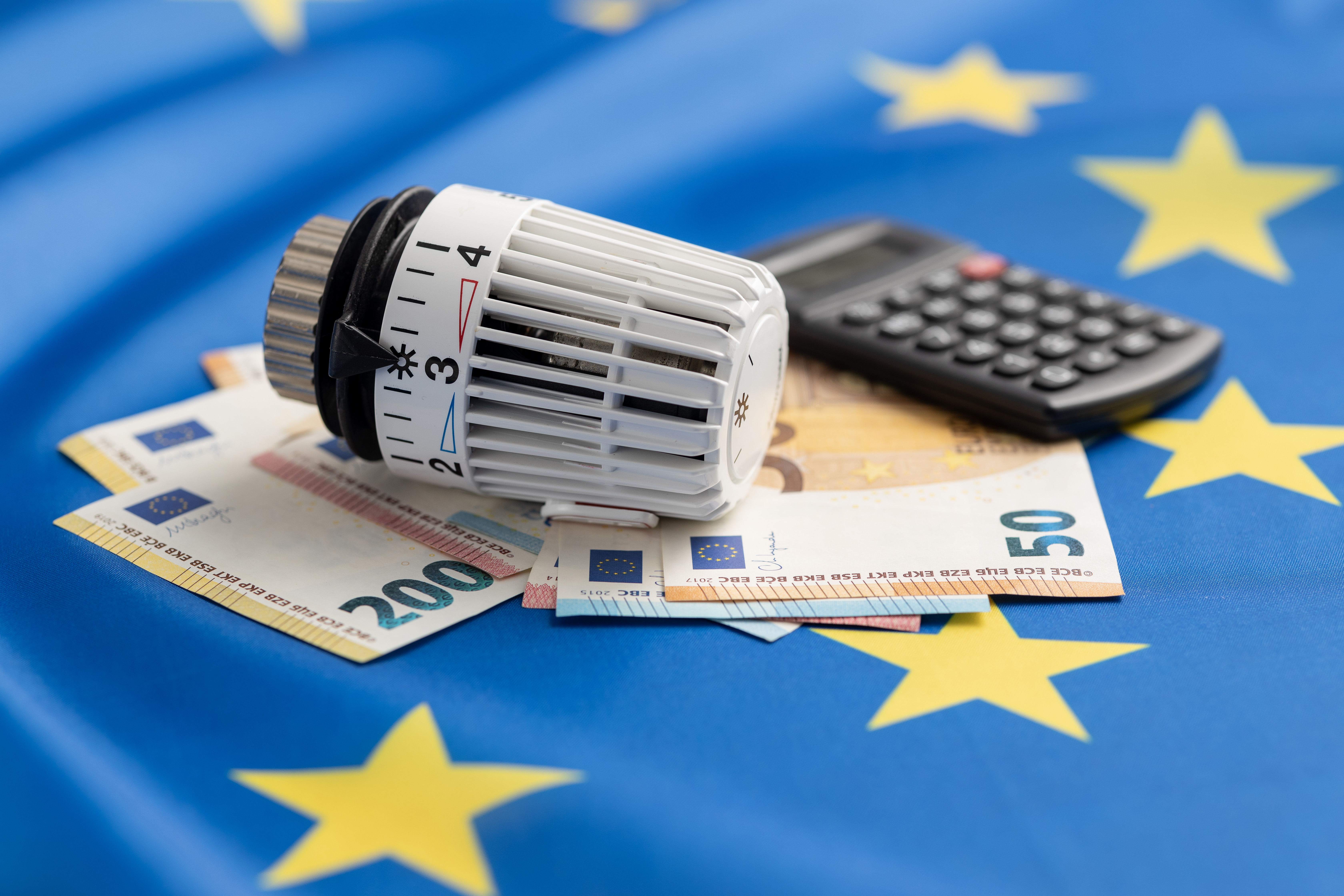 Heizungsventil und Geld vor EU-Flagge